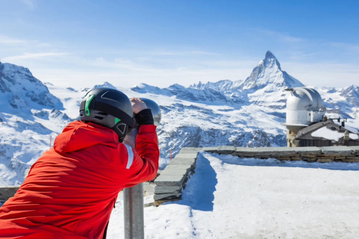 Male skier looking through binoculars at Gornergrat in Zermatt